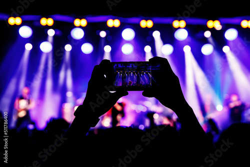 Holding a smartphone to record music concert. Mobile phone at a summer festival.