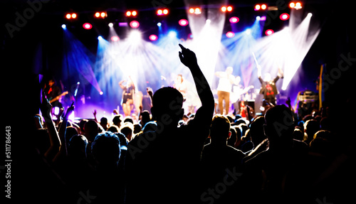 Silhouette of a young man on a concert with raised hand, big festival event.