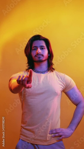 Forbidden gesture. Handsome man. Bad choice. No way. Muscular guy showing disagreement finger blue red neon light vibrant color glow isolated orange vertical. photo