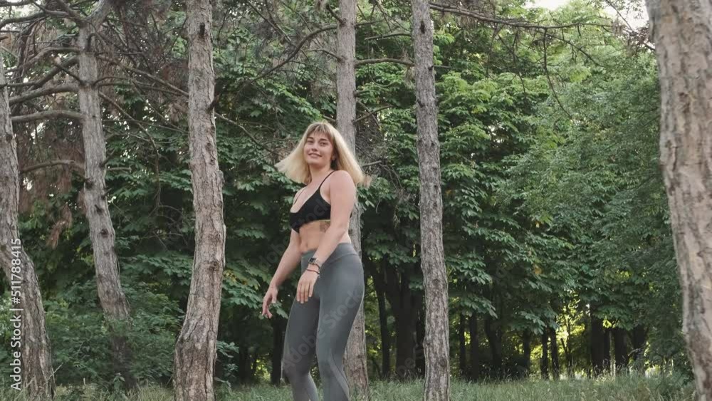 Flexible female gymnast doing acrobatic tricks in the park, slow motion Flexible female gymnast doing acrobatic tricks in the park, slow motion