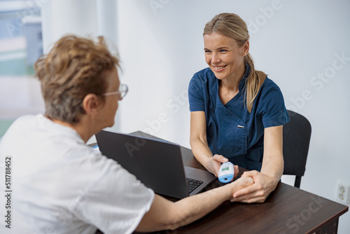 Doctor measures patient's temperature with non-contact thermometer during an appointment in clinic