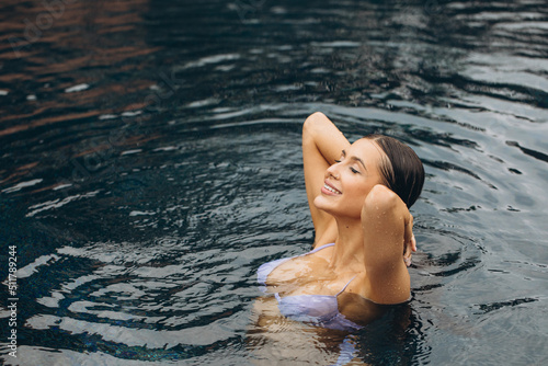 Beautiful and sexy woman in bikini posing in the pool, relaxation concept