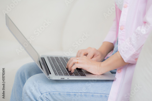 Closeup hands business woman work from home with laptop computer online to internet on sofa in living room, freelance girl using notebook sitting on couch with comfort and relax, lifestyles concept.