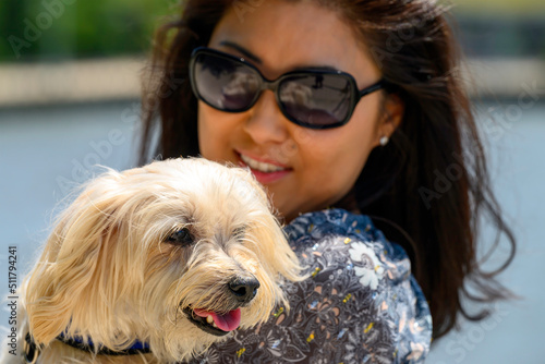 Beautiful Japanese Woman Snuggles Pet Dog on Bench in Close Up with Sunglasses photo