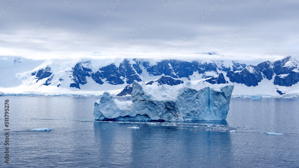 Iceberg floating in the bay in front of snow covered mountains at Portal Point in Antarctica