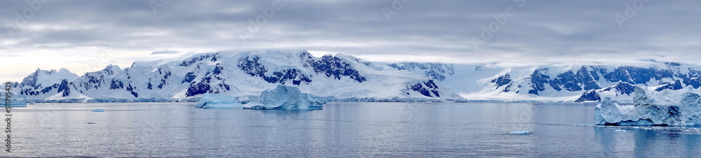 Panorama of icebergs floating in the bay, in front of snow covered moutains at Portal Point in Antarctica