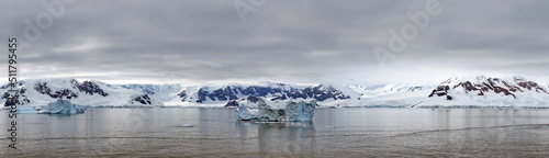 Panorama of icebergs floating in the bay, in front of snow covered moutains at Portal Point in Antarctica