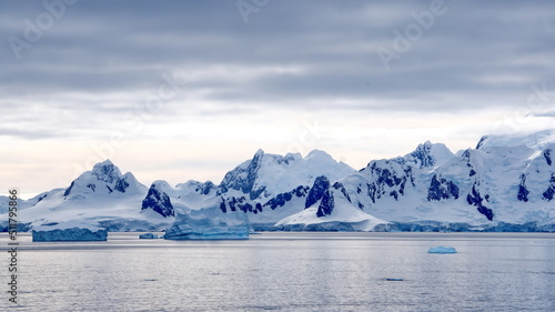 Icebergs floating in the bay in front of snow covered mountains at Portal Point in Antarctica