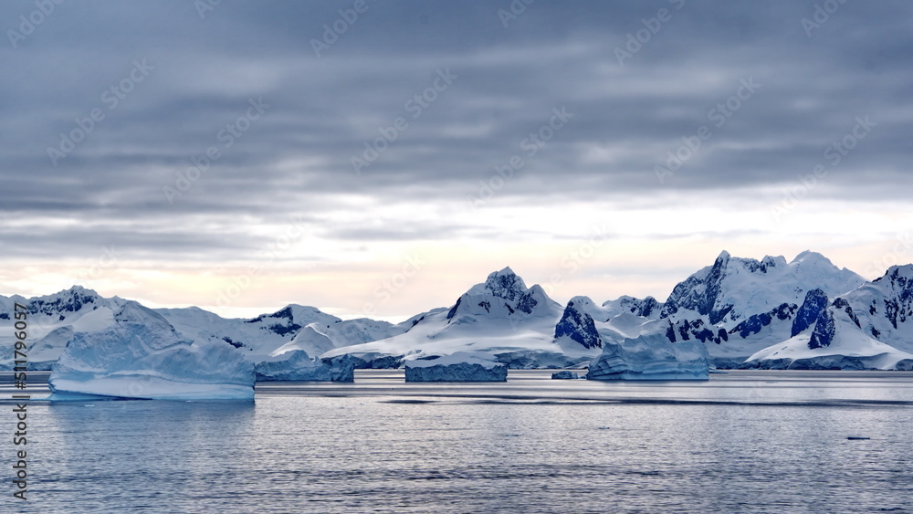 Icebergs floating in the bay in front of snow covered mountains at Portal Point in Antarctica