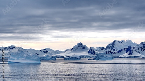 Icebergs floating in the bay in front of snow covered mountains at Portal Point in Antarctica © Angela