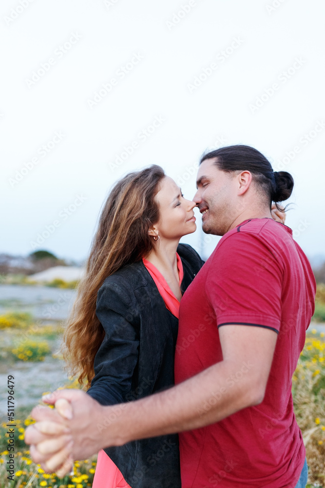Fototapeta premium Portrait of lovely middle-aged couple looking on each other and hugging while standing on grass in summer park.