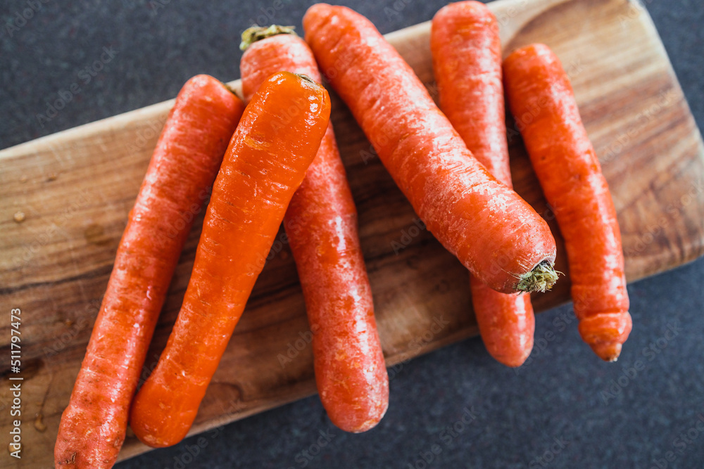 close-up of fresh carrots on wooden chopping board, simple ingredients concept close-up of fresh carrots on wooden chopping board, simple ingredients concept