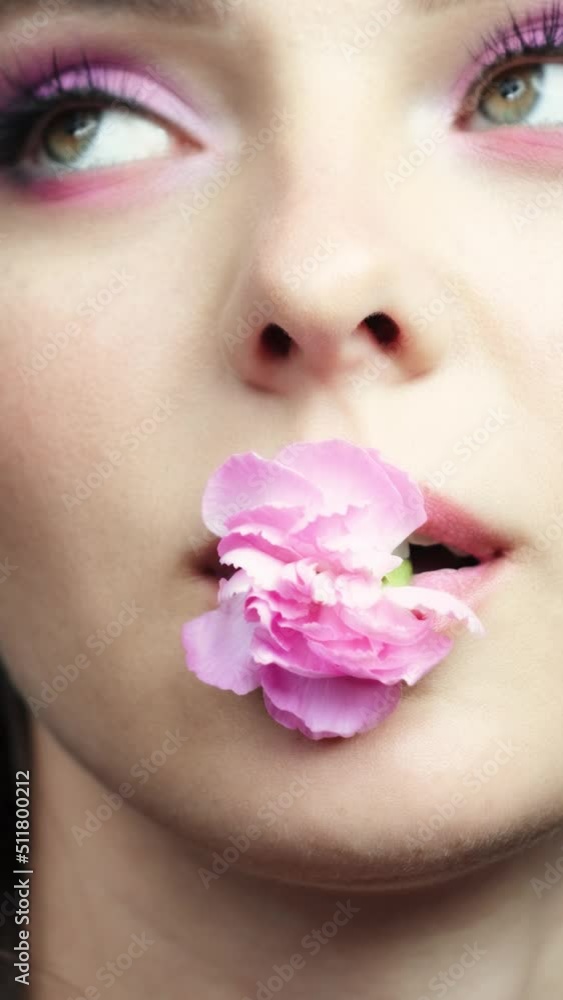 Closeup slow motion vertical video of female with a pink carnation in mouth. Closeup slow motion vertical video of female with a pink carnation in mouth.