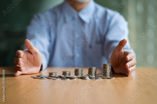 Businessman protecting a pile of coins on money-saving and property insurance concept.