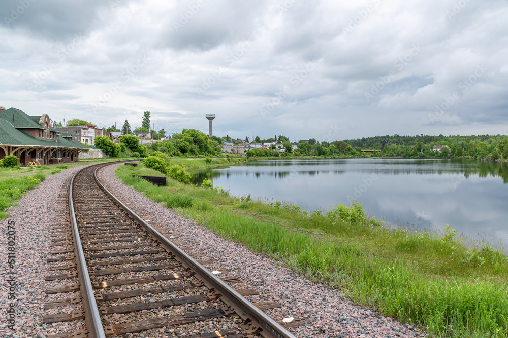 A railway track curves its way around a small lake up to the station in the small former mining town of Cobalt, Ontario on a gloomy day. A railway track curves its way around a small lake up to the station in the small former mining town of Cobalt, Ontario on a gloomy day.