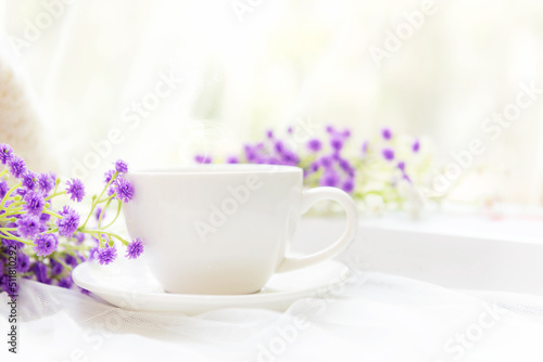 Coffee morning.  White steaming cup of hot coffee for relax after working hobbies crochet on white wooden near window with flowers.