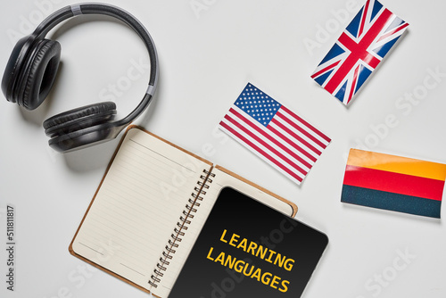 Learning foreign languages. Audio language courses. Background from countries flags and headphones white on the table.