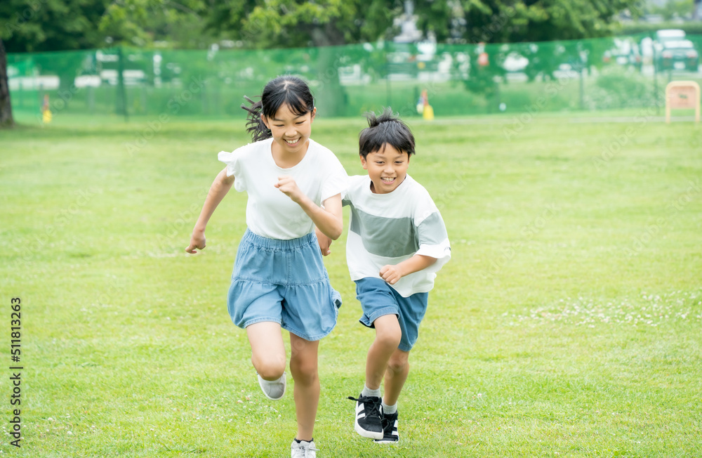 Obraz premium 芝生の公園を走るアジア人の子供