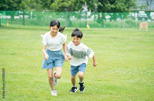 芝生の公園を走るアジア人の子供