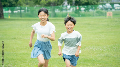 芝生の公園を走るアジア人の子供
