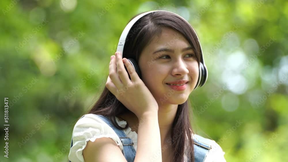 Beautiful young woman girl in beige shirt posing in Green city Park background , Smile girl Listening Music with Headphones feeling Touching Happiness. People lifestyle concept. Mock up copy space. Beautiful young woman girl in beige shirt posing in Green city Park background , Smile girl Listening Music with Headphones feeling Touching Happiness. People lifestyle concept. Mock up copy space.