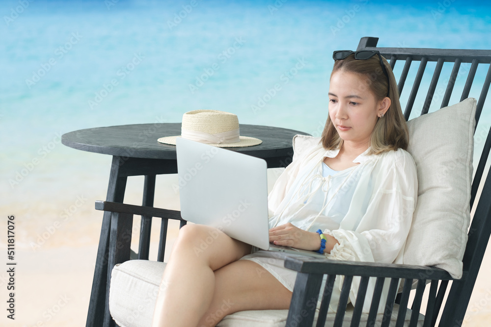 Work from anywhere concept. woman, female freelancer in straw hat working on laptop, smile and happy work success while sitting on the tropical sandy beach.