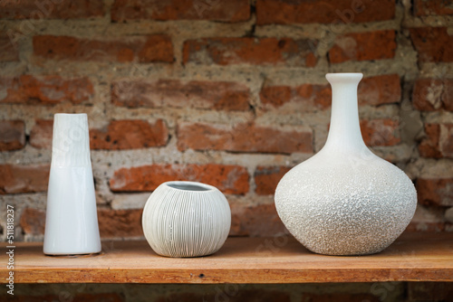 Fotografija Set of crockery and ceramic kitchenware which is kept on the wooden shelf in red brick wall storage room