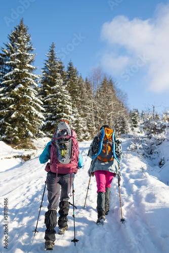 Two women walk with snowshoes on the backpacks, winter trekking © zhukovvvlad