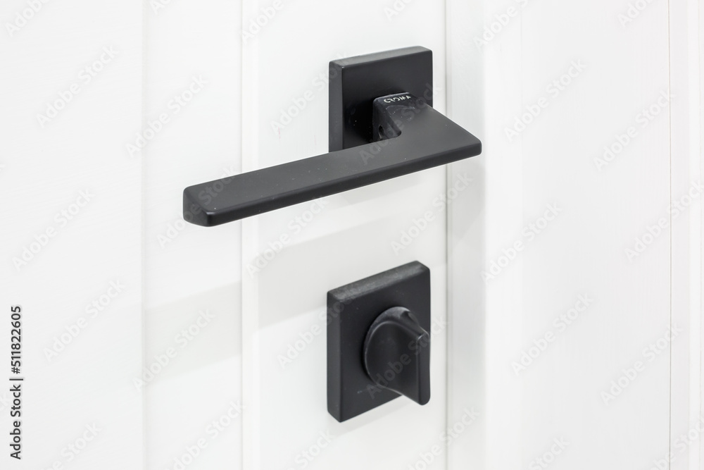 Modern black door handle on white wooden door in interior. Knob close-up elements. Door handle, fittings for interior design Modern black door handle on white wooden door in interior. Knob close-up elements. Door handle, fittings for interior design