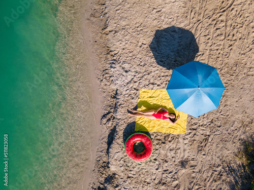 overhead view woman sunbathing at sandy beach photo