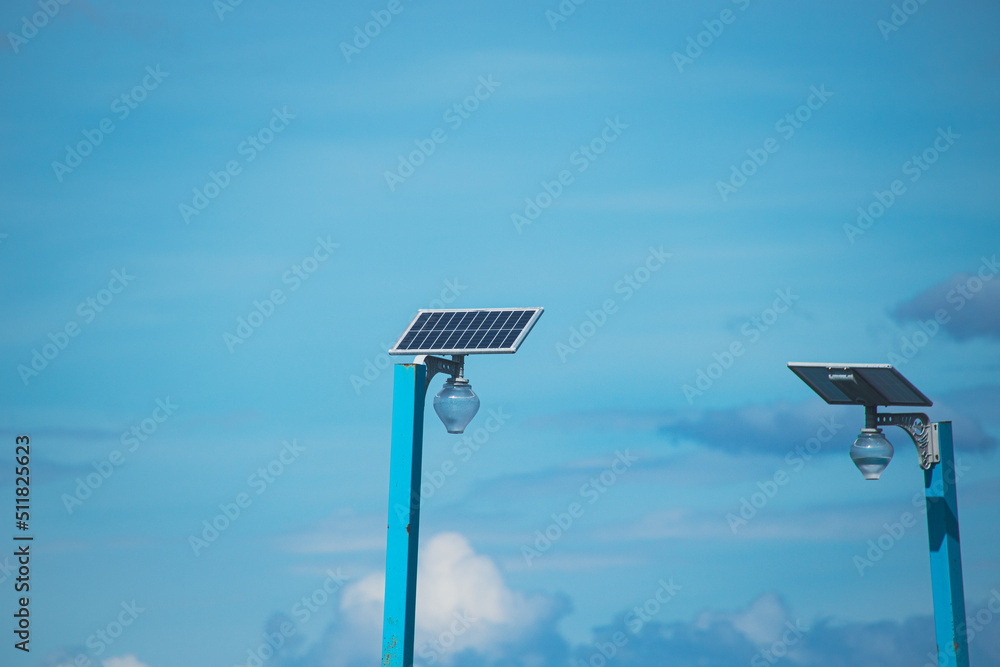 Two solar panels powering a lamp post against the blue summer sky Two solar panels powering a lamp post against the blue summer sky