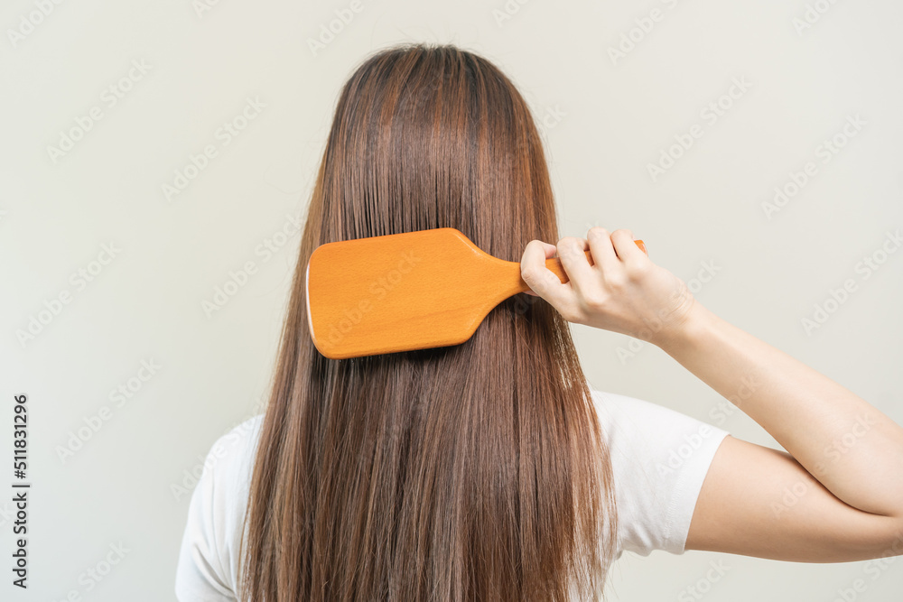 Fototapeta premium Health hair care, beauty makeup asian woman hand in holding hairbrush and brushing, combing her long straight hair in the morning routine after salon treatment, hairstyle. Isolated on white background