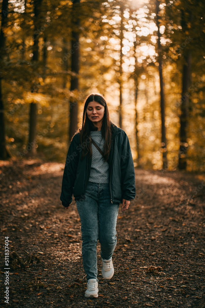 A young girl is smiling and looking into the camera while walking in the autumn forest. Concept of easy hiking in the woods A young girl is smiling and looking into the camera while walking in the autumn forest. Concept of easy hiking in the woods