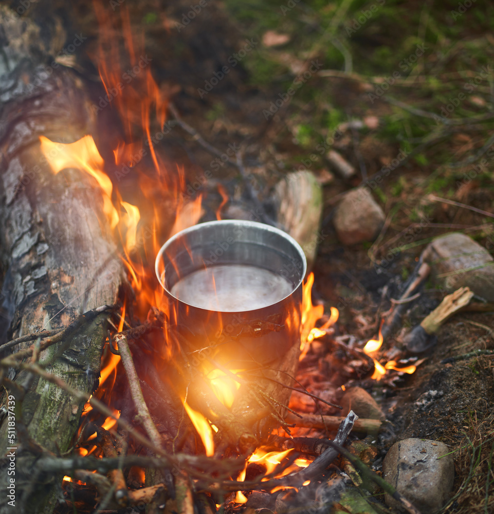 Boiling water at the camp fire. Concept of cooking food during night stay in the camp. Summer adventures in the woods Boiling water at the camp fire. Concept of cooking food during night stay in the camp. Summer adventures in the woods
