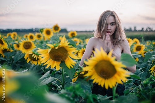 Young, slender, with loose hair in a field of sunflowers at sunset