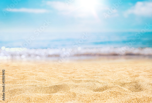 Beautiful background for summer vacation and travel. Golden sand of tropical beach, blue sky and blurred glare of sun on waves of surf.
