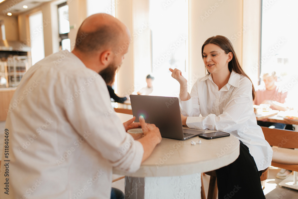 Fototapeta premium A woman is interviewing a new employee in a coffee shop using a laptop.