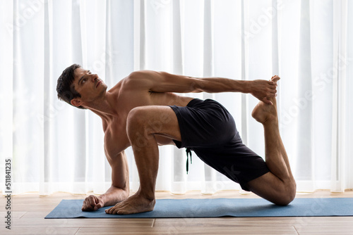Young yoga man doing stretching legs during morning routine