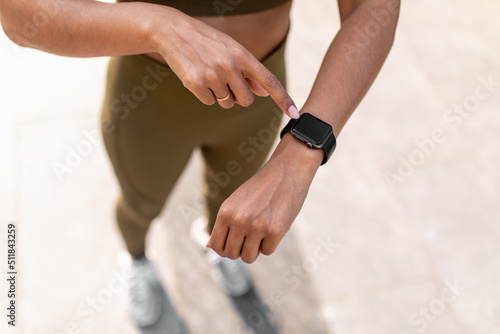 Young black woman using fitness tracker with mockup, checking heart rate and burned calories while jogging on street