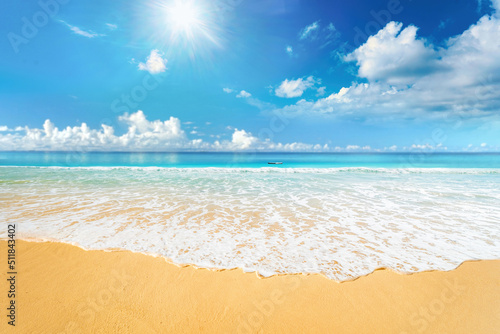 Beautiful natural background image of tropical beach. Blue sky with sun and clouds  turquoise ocean with rolling surf with white foam and gold sand. Harmony of clean environment.