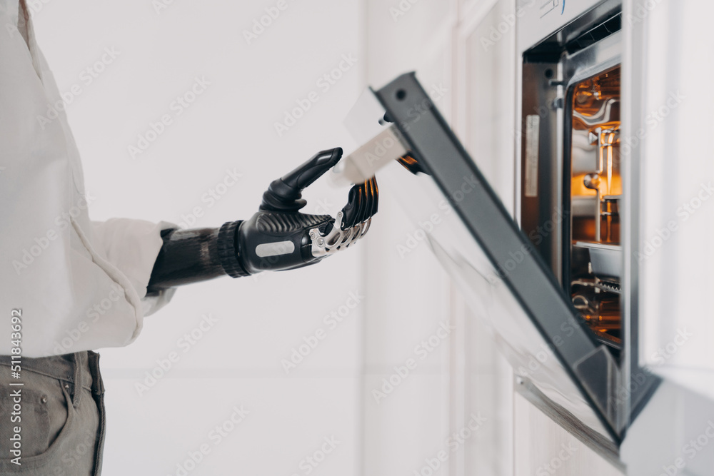 Female amputee is cooking using futuristic high technology bionic prosthesis. Daily routine. Female amputee is cooking using futuristic high technology bionic prosthesis. Daily routine.