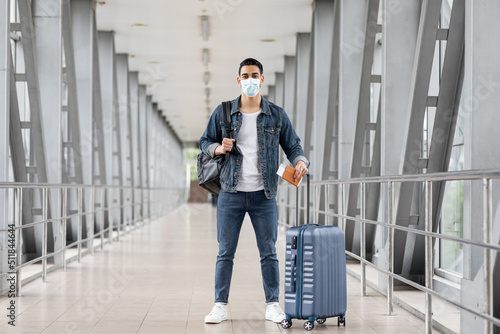 Young Arab Man Wearing Medical Face Mask Standing With Luggage In Airport