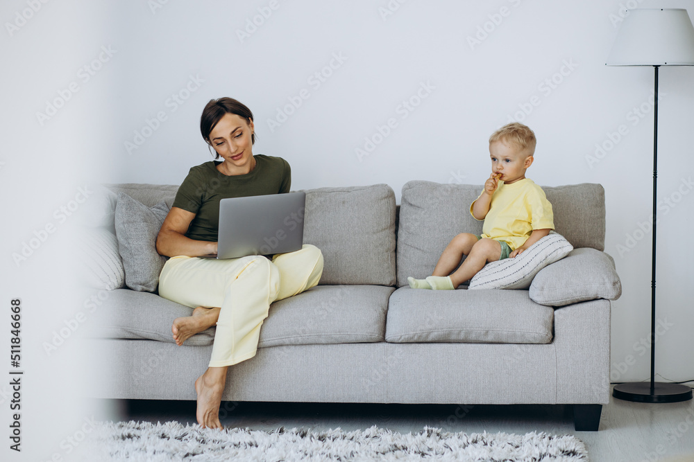 Mother with her son sitting on sofa and using laptop Mother with her son sitting on sofa and using laptop