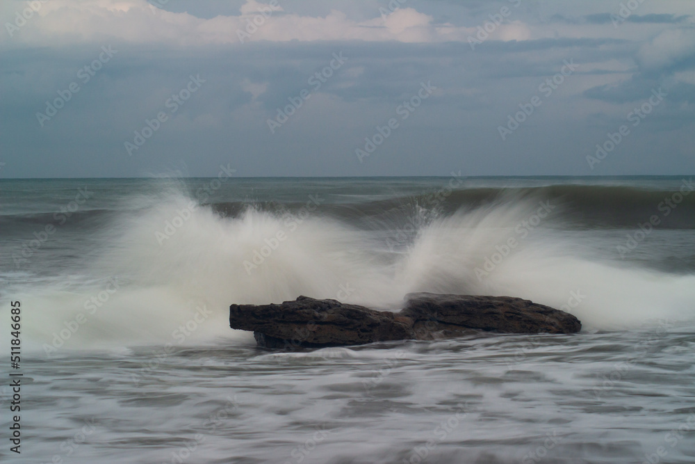 waves crashing against the rocks on the beach during the day