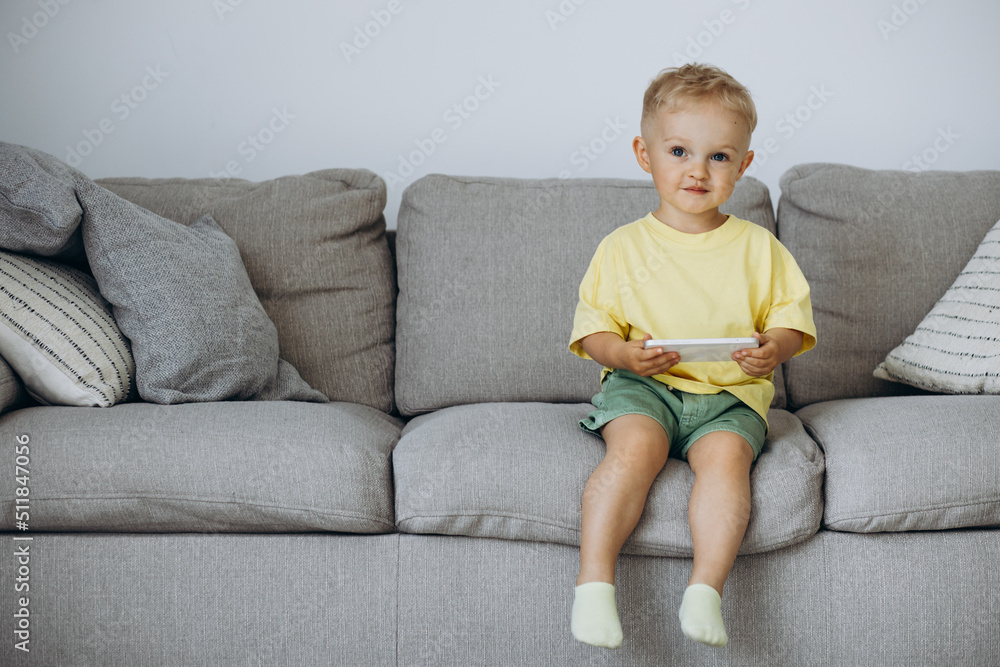Little boy sitting on sofa and using phone Little boy sitting on sofa and using phone