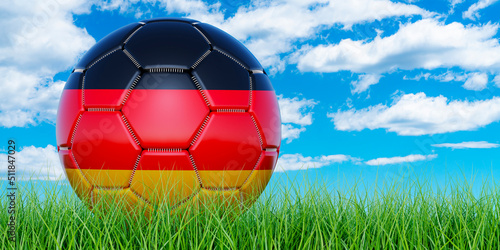 Soccer ball with German flag on the green grass against blue sky  3D rendering