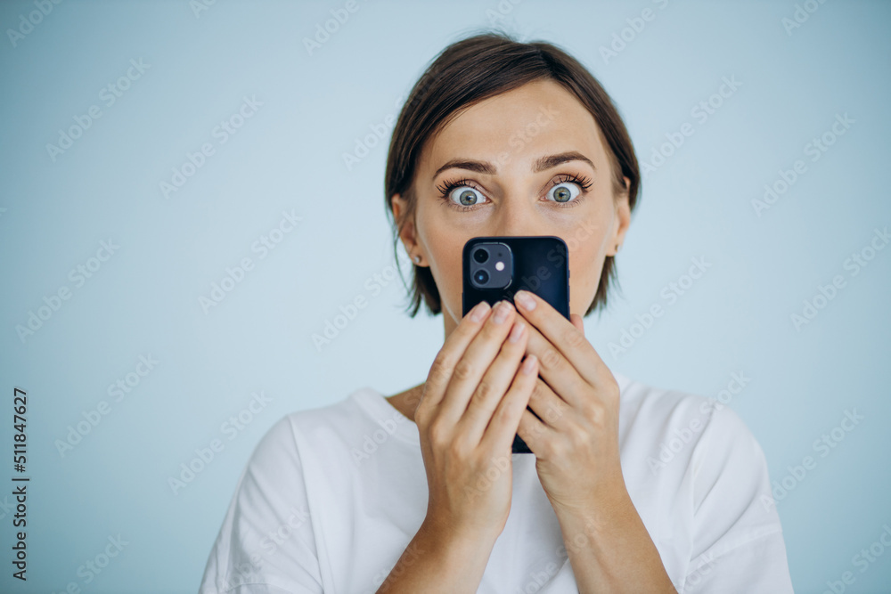 Portrait of woman holding mobile phone isolated on blue background Portrait of woman holding mobile phone isolated on blue background