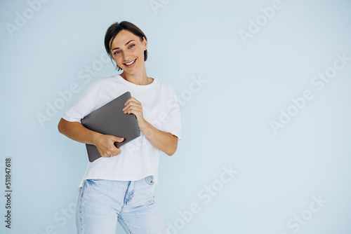 Young woman standing with laptop isolated on blue background