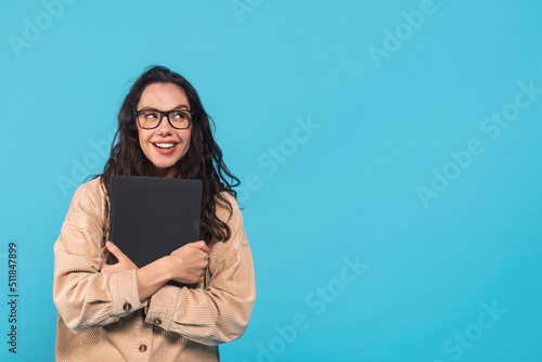 Glad happy millennial european female brunette blogger in casual and glasses hugging laptop, looking at empty space © Prostock-studio