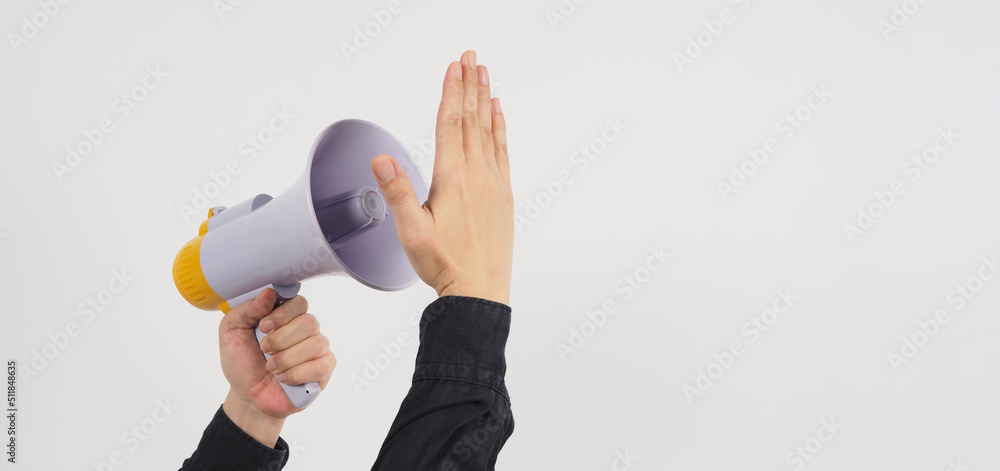 Megaphone in male left hand and another hand cover-up. He wears a black shirt on white background. Studio shooting. Megaphone in male left hand and another hand cover-up. He wears a black shirt on white background. Studio shooting.